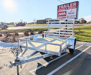 A new Silver Ox single axle aluminum utility trailer parked at a dealership lot, featuring an open bed with wood decking and metal frame.