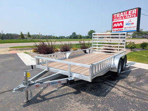 Aluminum Utility trailer with wooden floor on a paved area with a clear sky.