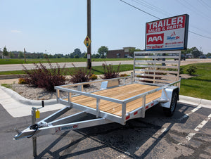 Silver OX trailer with wooden floor in front of a Trailer Sales & Parts sign.