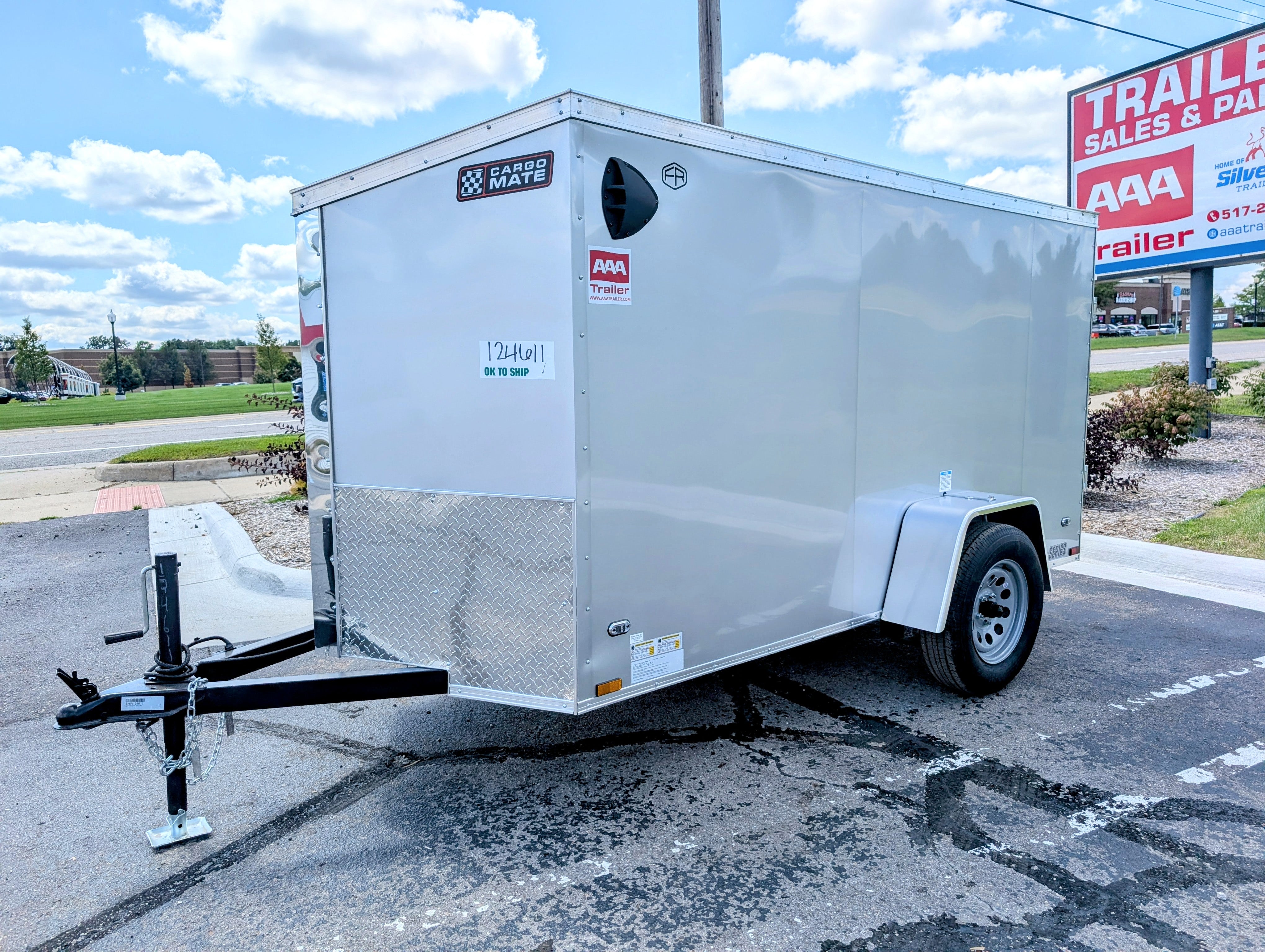 White enclosed trailer parked in a lot with a clear sky. AAA Trailer