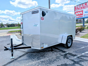 White enclosed trailer parked in a lot with a clear sky. AAA Trailer
